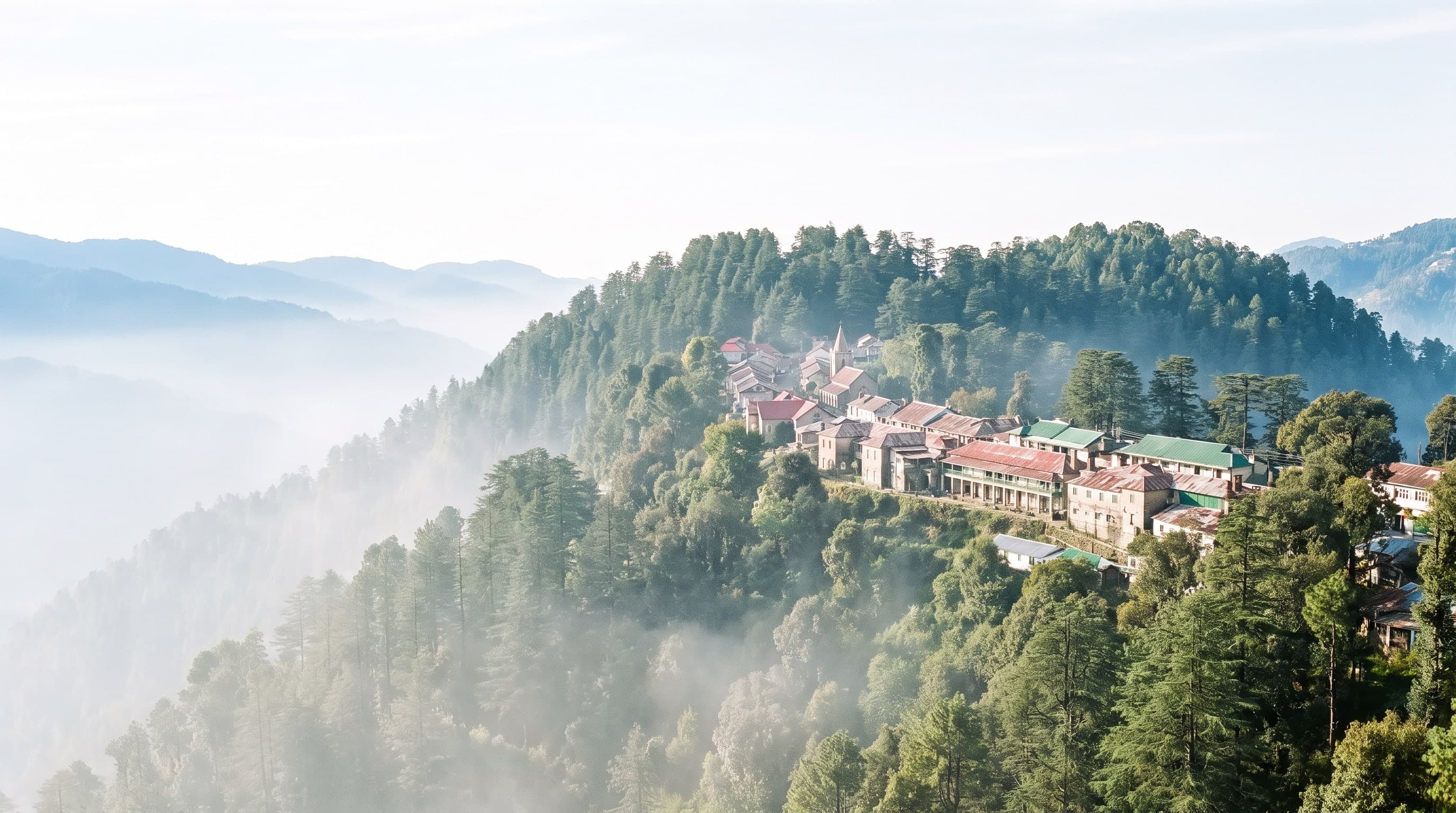 A small hill-station town of tin roofs and a church spire following the crest of a deodar ridge above a valley of morning mist, forest closing in on both sides of it