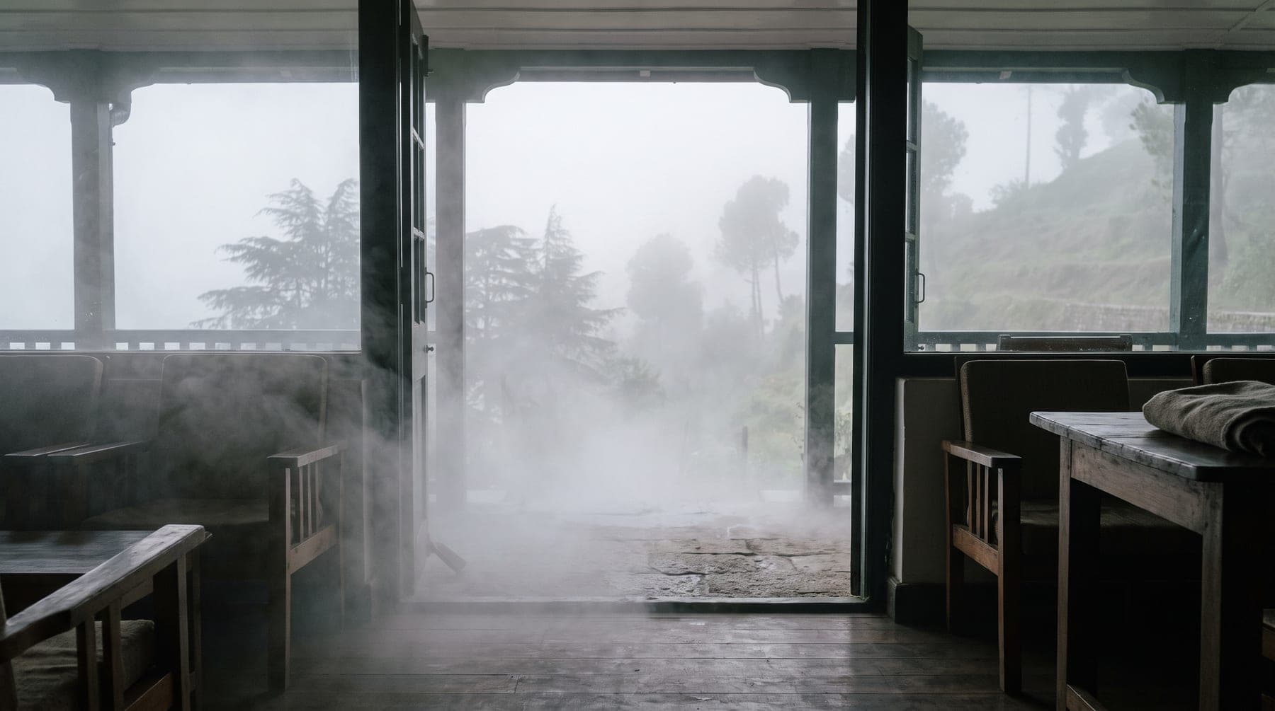 Cloud drifting through the open doors of a hill-station verandah onto a wooden floor